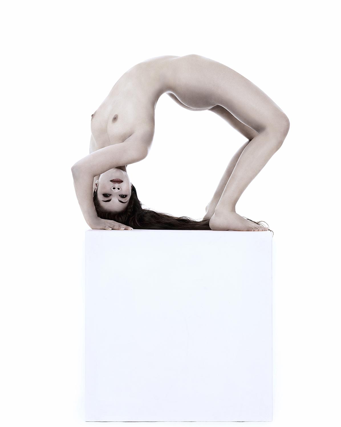 La contorsionniste pose pour une photographie de Gerard Rancinan sur un cube blanc.