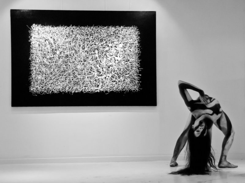 La contorsionniste fait une posture à côté d'un tableau dans une galerie du village suisse.
