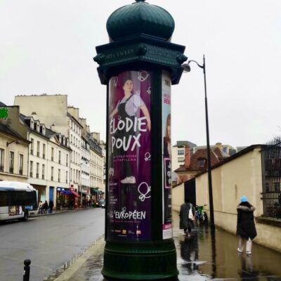 Photo de l'affiche : Elena Ramos. L'humoriste Élodie Poux et son spectacle en colonne Morris dans Paris en 2023.
