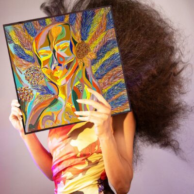 Lila Ramos photographiée par sa soeur, tient l'un de ses tableaux devant son visage comme une transfiguration.