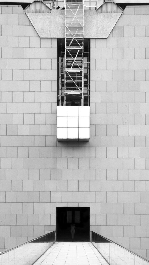 Une photographie d'un détail de l'architecture de La Cité des Sciences et de l'Industrie de la Villette et d'une silhouette dans l'ombre.